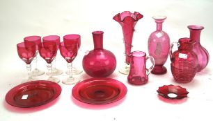 A collection of cranberry glassware, including a pair of vases, wine glasses, beakers, two jugs,