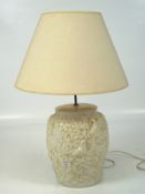 A large contemporary white glazed table lamp, adorned with scenes depicting birds and leaves,