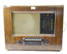 A vintage 20th century radio, having a central speaker to the front and knobs and dials below,