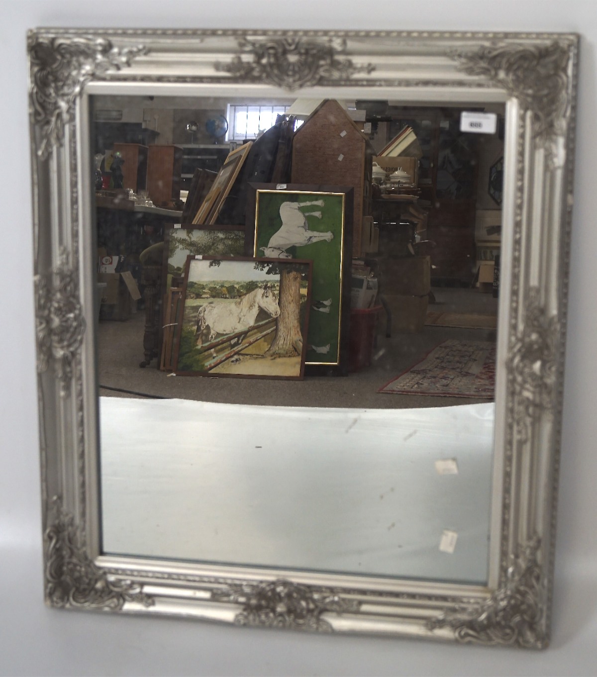 A contemporary silvered wall mirror with moulded ornate details,