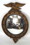 A reproduction Regency stye round convex mirror with a studded frame surmounted by an eagle,