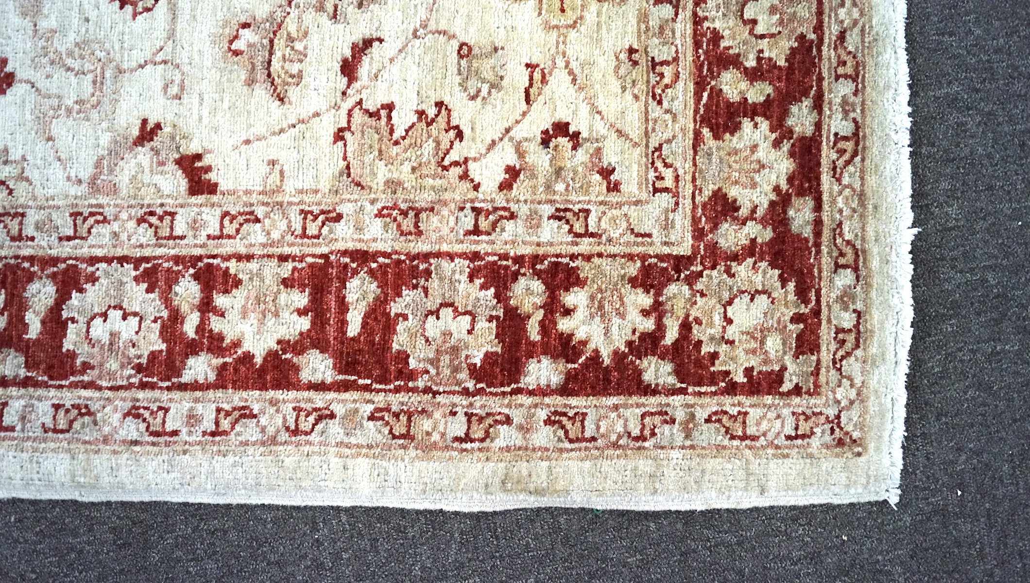 A woven Eastern rug, decorated with floral patterns on a beige ground, encircled by a red border, - Image 2 of 3