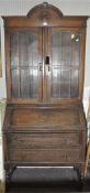 An early 20th century bookcase bureau with leaded glazed doors below a domed pediment,