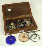 A wooden box containing a selection of costume jewellery, including a silver and enamel compact,