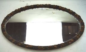 A 20th century bevelled edge wall mirror, of oval form, the frame decorated with fruit,