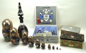 An assortment of collectables, including Russian dolls, a glass decanter, two tin boxes,