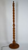A honey coloured wood sectional barley twist standard lamp on a round base,