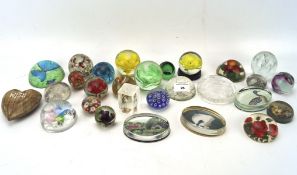 A collection of paperweights, including glass, plastic and wooden examples,