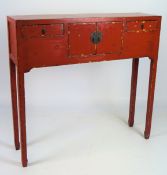 A shallow Chinese hall cabinet lacquered red, with two small drawers flanking double doors,