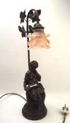 A resin and metal lamp featuring a seated women reading beneath four leaves,