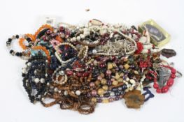 A selection of costume jewellery, including floral brooches, beaded necklaces, a Stratton compact,