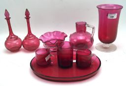 A collection of cranberry glassware, including vases, tray, cups and more,