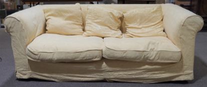 A large sofa and three scatter cushions upholstered in yellow fabric with textured leaf pattern,