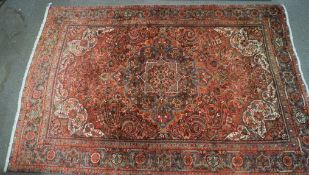 A large red ground rug with an ornate pattern in shades of blue, cream and green,