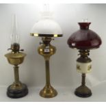 Three Victorian oil lamps, all with brass column frames on circular bases,
