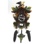 A contemporary cuckoo clock decorated and painted in relief with birds and leaves, with weights,