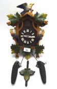 A contemporary cuckoo clock decorated and painted in relief with birds and leaves, with weights,