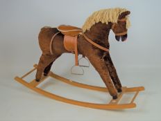 A contemporary rocking horse upholstered in chestnut brown, with painted wooden muzzle and hooves,