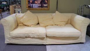 A large sofa and three scatter cushions upholstered in yellow fabric with textured leaf pattern,