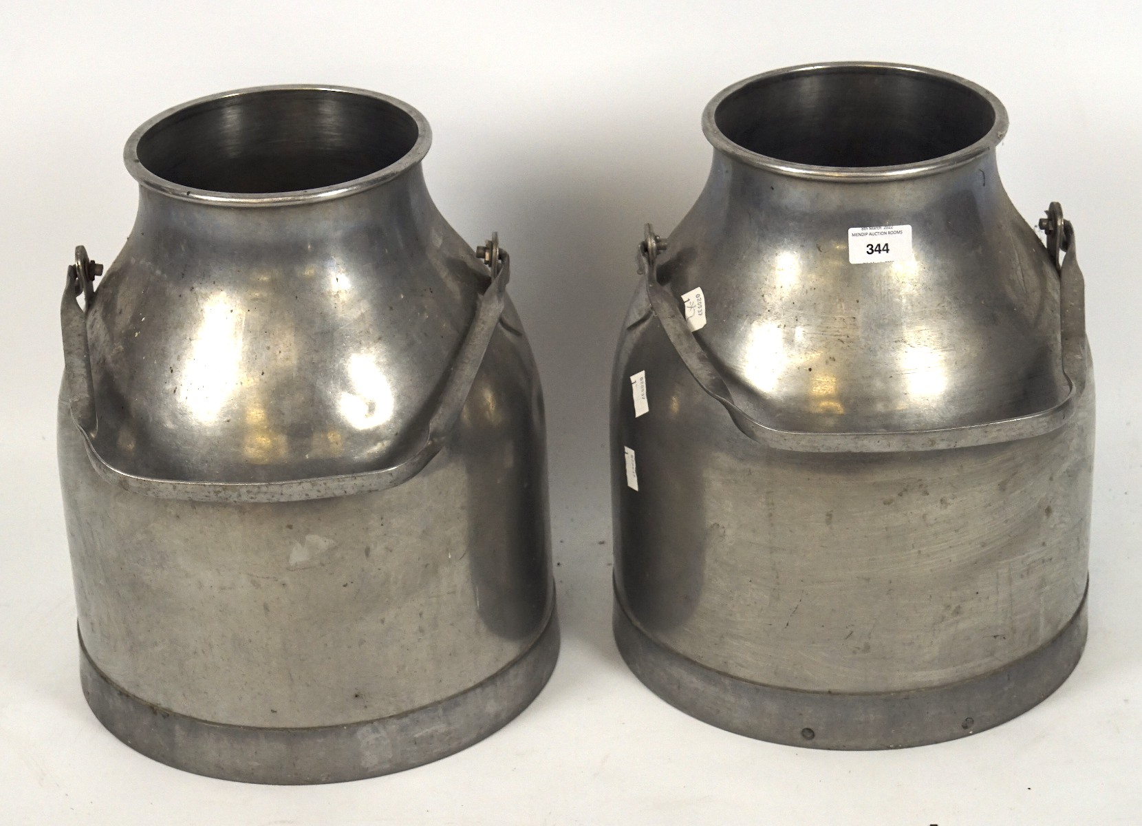 Two contemporary stainless steel milk pails, each with a single swing handle,