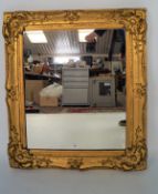 A heavy gilt plaster and wood framed wall mirror moulded with foliate details,