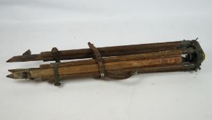 A surveyor's wooden tripod with green painted metal fixings,