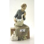 A Nao figure of a seated woman holding a basket containing a duck,