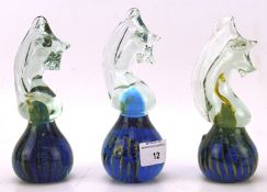 A group of three Mdina glass paperweights, all modelled as seahorses, in blue and green,