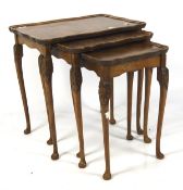 An early 20th century burr wood nest of three tables, each with cabriolet supports,