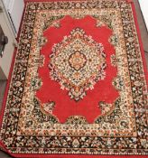 A 20th century floor rug, with foliate border and centre on a red ground,