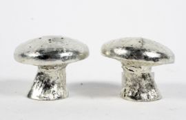 A pair of white metal cruets in the form of mushrooms,
