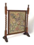 A 20th century wooden fire screen with barley twist supports and needlework panel,