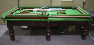 A nine foot mahogany billiard table with green baize, with a selection of cues, cue holder,