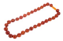 A faux amber necklace, uniform strand of circular beads.