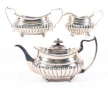 A George III three piece silver tea set, each with half gadrooned bodies raised upon four feet,