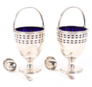 A pair of ornate George V silver sugar bowls with blue glass liners,