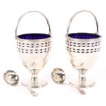 A pair of ornate George V silver sugar bowls with blue glass liners,