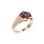 A 9ct gold and red garnet daisy ring, set with seven round cut garnets with textured shoulders.