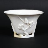 A Chinese Ching dynasty porcelain blanc de chine libation cup, with moulded plum blossom,