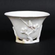 A Chinese Ching dynasty porcelain blanc de chine libation cup, with moulded plum blossom,