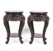 A pair of early 20th century Chinese carved lamp tables with under tier raised on carved cabroile