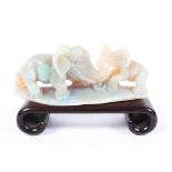 A Oriental carved opal model of an elephant and calf, mounted on a hardwood plinth stand. 9cm.