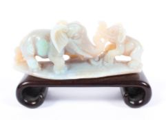 A Oriental carved opal model of an elephant and calf, mounted on a hardwood plinth stand. 9cm.