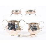 A matching silver sugar bowl and cream jug with two open salts and a set of sugar tongs,