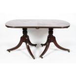 A Regency style twin pillar mahogany dining table, the top of oval form and one additional leaf,