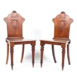 A pair of Edwardian mahogany hall chairs with shield shaped backs on turned legs