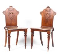 A pair of Edwardian mahogany hall chairs with shield shaped backs on turned legs