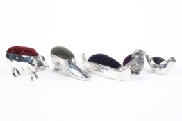 A collection of five silver pin cushions, to include a Pig, shoe, Boat and two Birds,