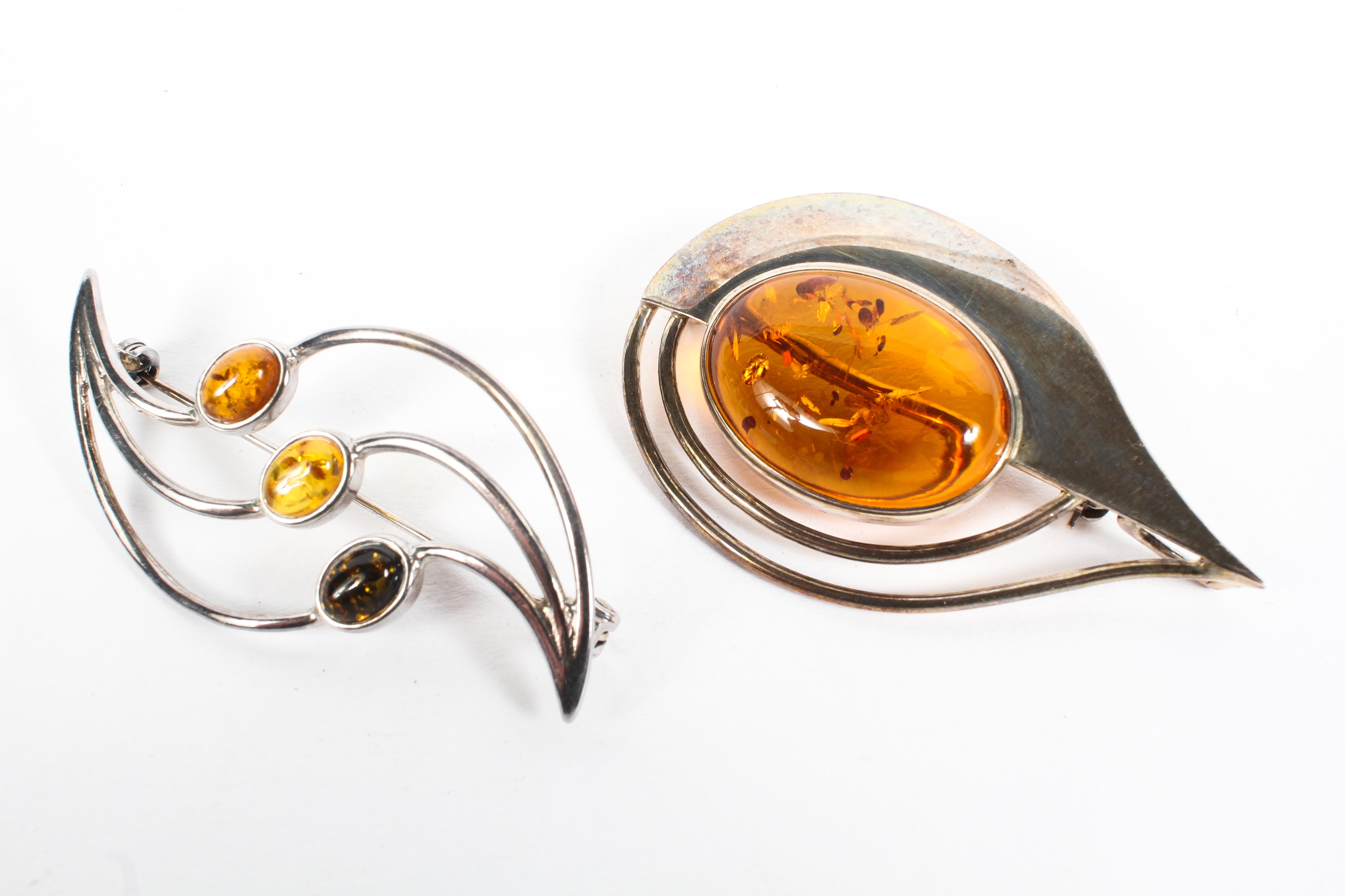 Two contemporary amber brooches set in white metal, each of abstract design, both stamped 925,