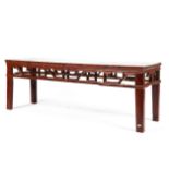 A late 19th century cherry wood elongated table with pierced geometric frieze raised on square